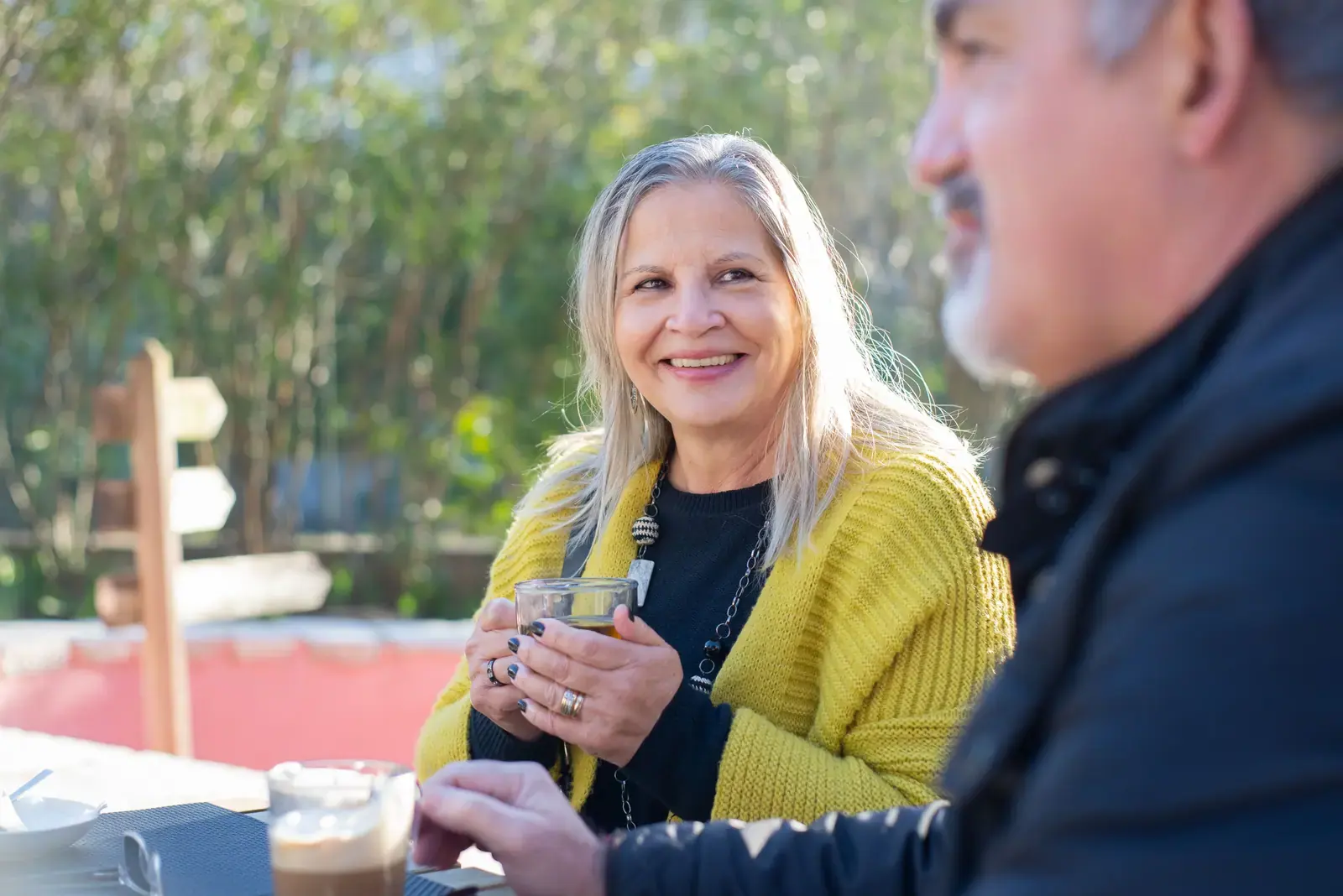 Two people talking over coffee at an outdoor table