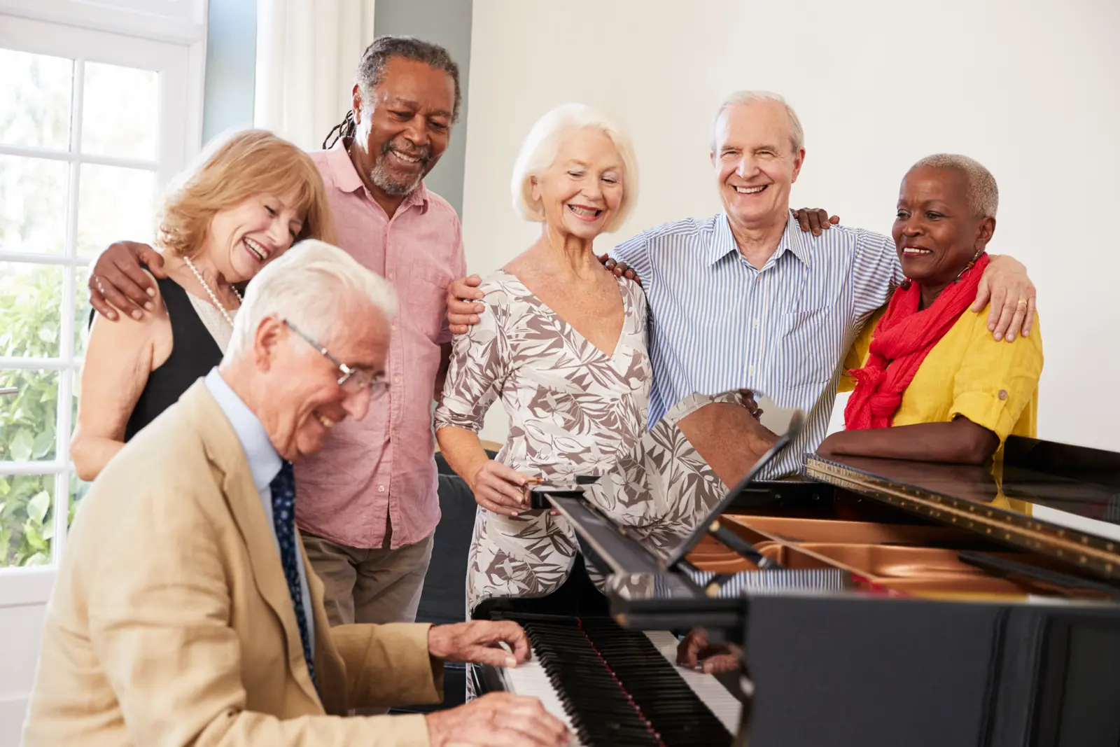 A group of older adults singing together beside a piano